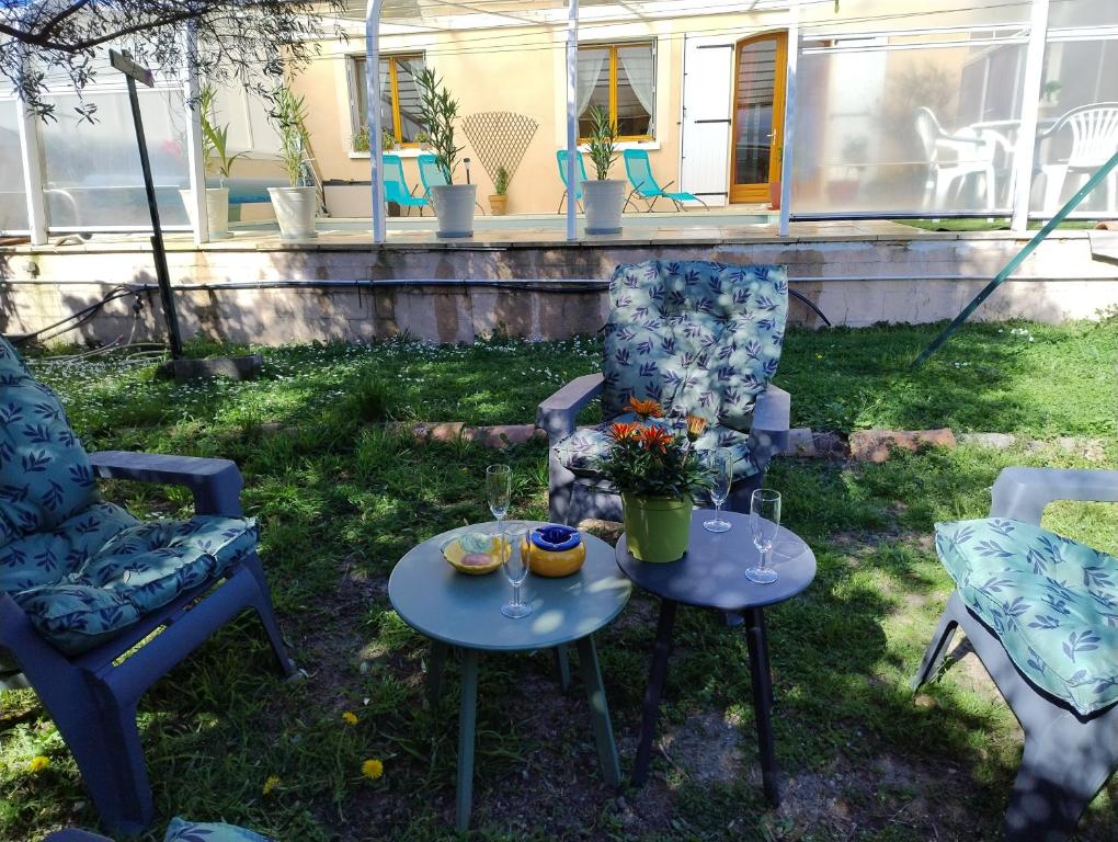 - une terrasse avec 2 chaises et 2 tables avec des verres à vin dans l'établissement Gites l’Olivier avec piscine, à Vallon-Pont-dʼArc
