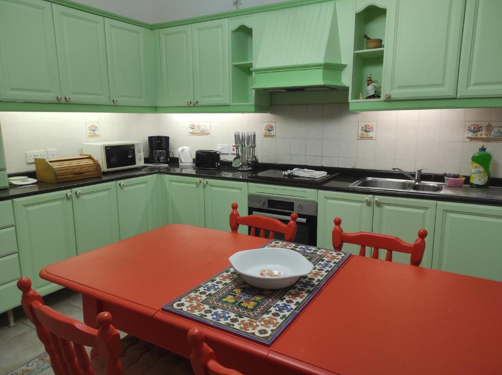 a kitchen with green cabinets and a red table with a bowl on it at Ta' Marija Home in Sliema