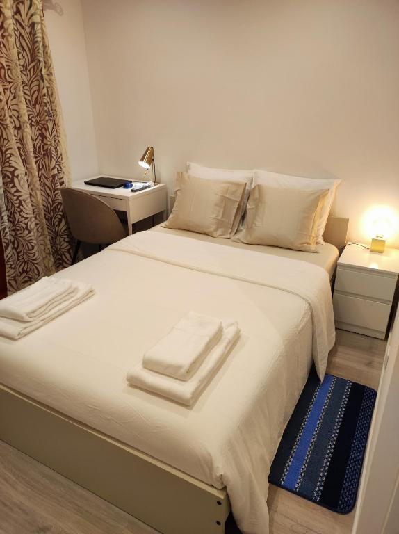 a bedroom with a large bed with towels on it at Vista Panorâmica Amadora RC in Amadora