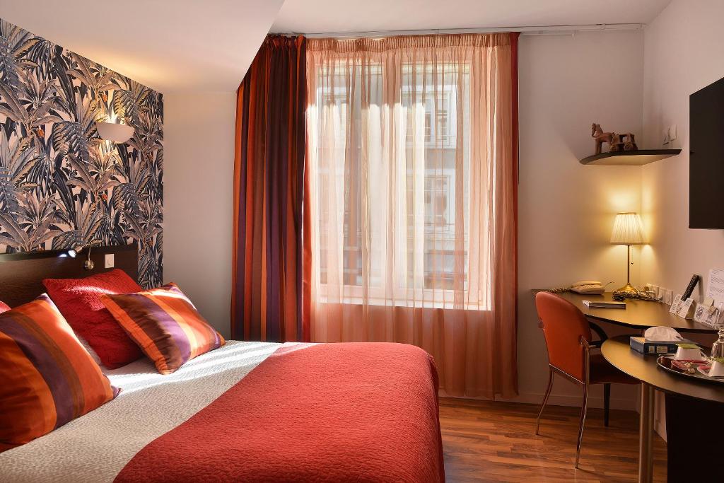 una camera da letto con un letto, una scrivania e una finestra di Logis Hôtels Le Saint Georges a Vendôme