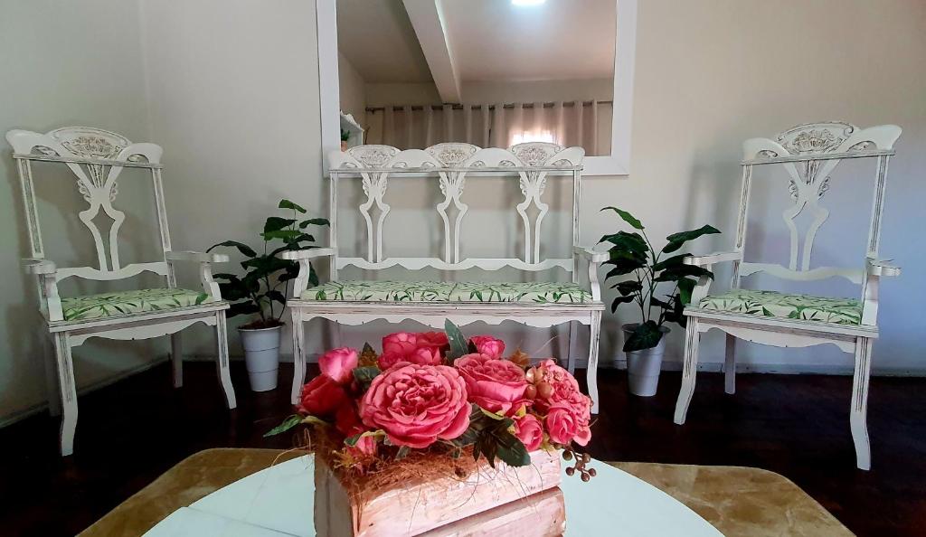 een kamer met 2 stoelen en een tafel met een boeket rozen bij La Casina in Uruguaiana