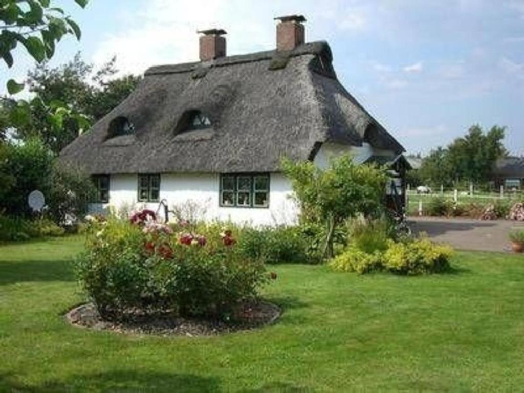 uma casa com telhado de palha num quintal em Kleines historisches Reetdachhaus auf altem Deich em Helse