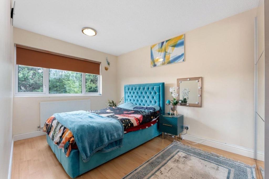 Un dormitorio con una cama azul y una ventana en Tranquility en Cheam