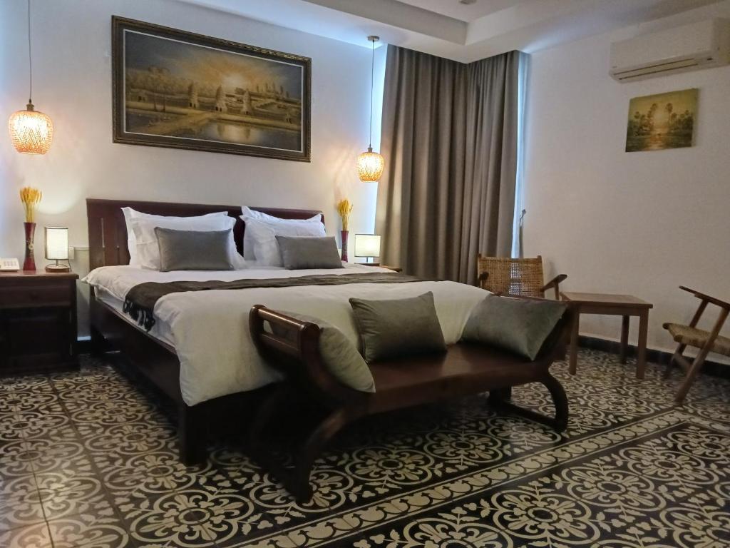 um quarto de hotel com uma cama e um banco em Andy's Place em Siem Reap