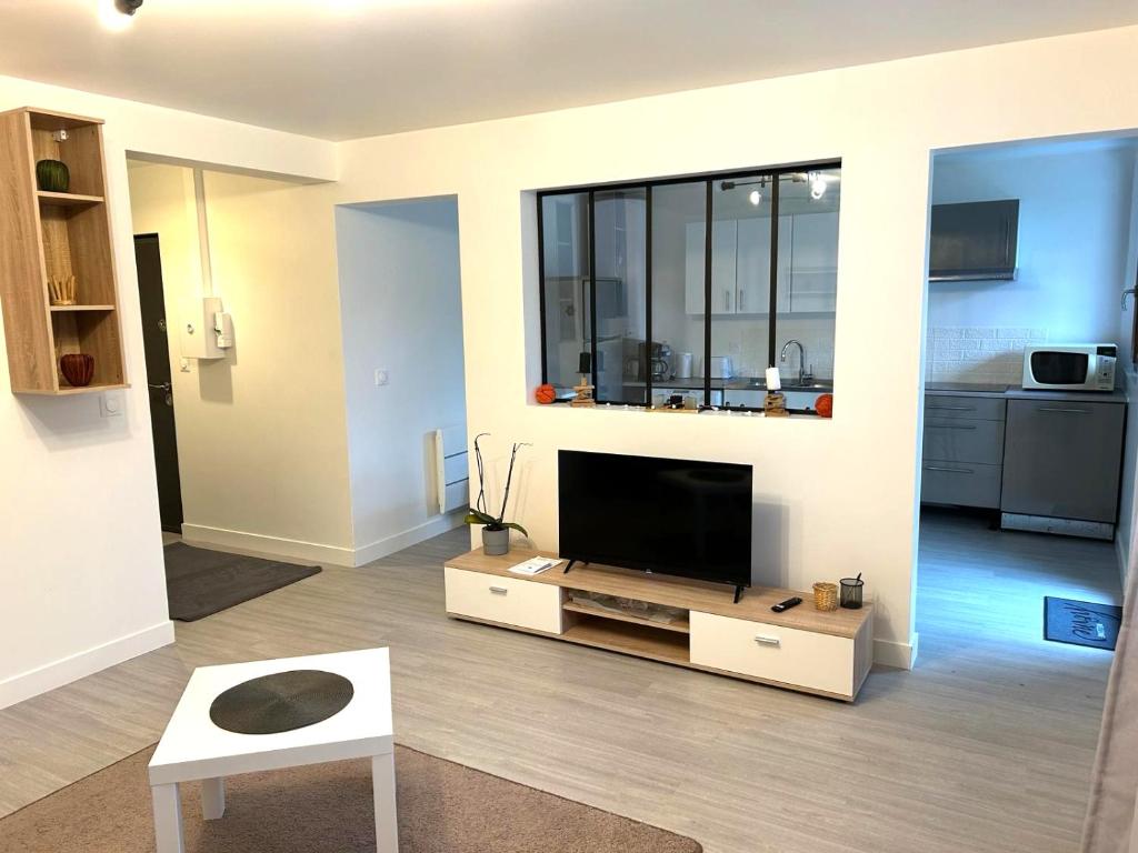 a living room with a flat screen tv on a stand at Appartement calme Antony, terrasse, vue jardin, proche Paris et Orly in Antony