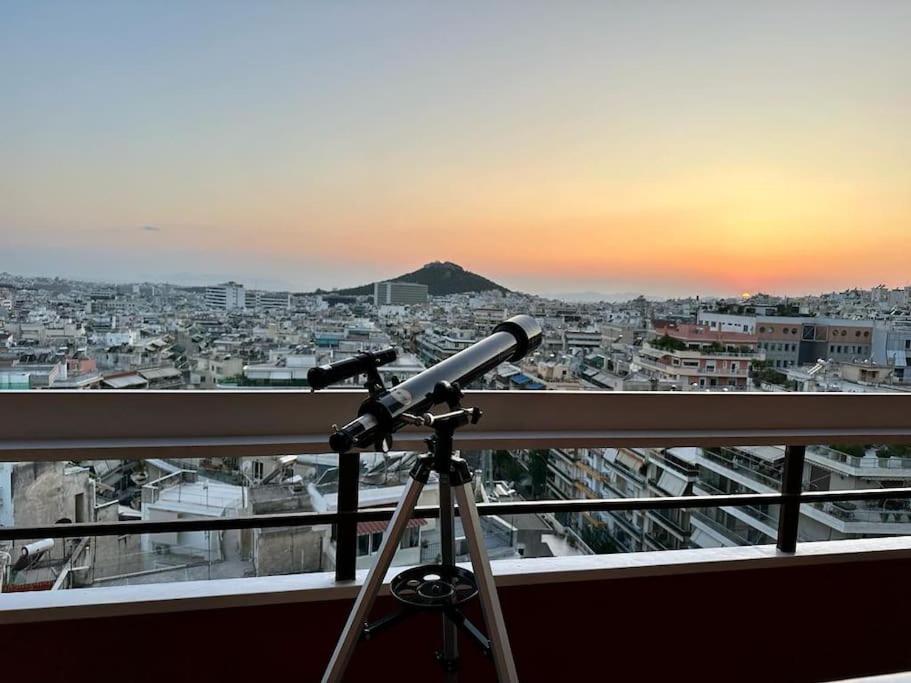 un telescopio su un balcone che guarda una città di Apollo Tower Athens Center 360oView Luxury Apt ad Atene