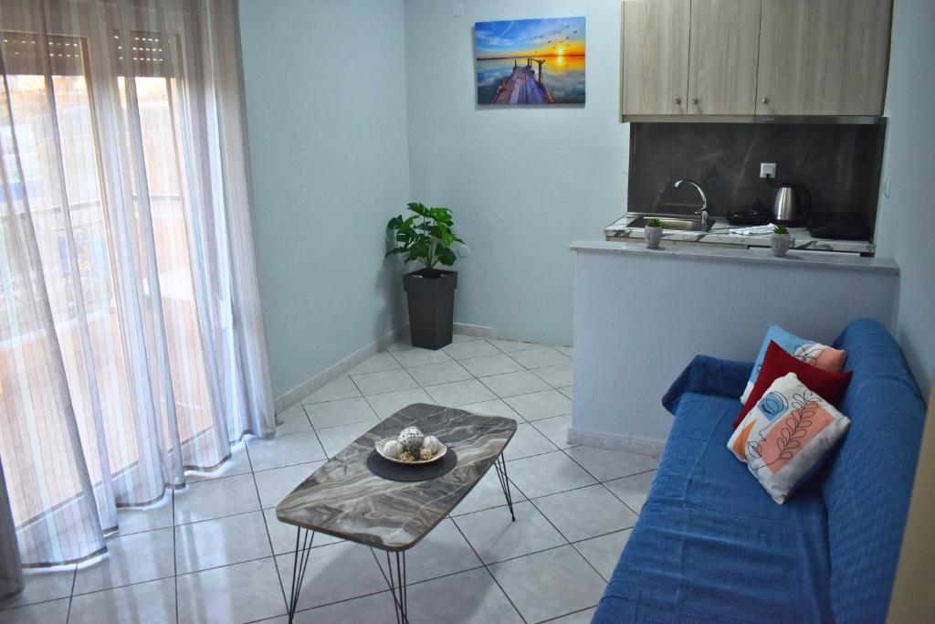 a living room with a blue couch and a table at Venice Apartments in Limenaria
