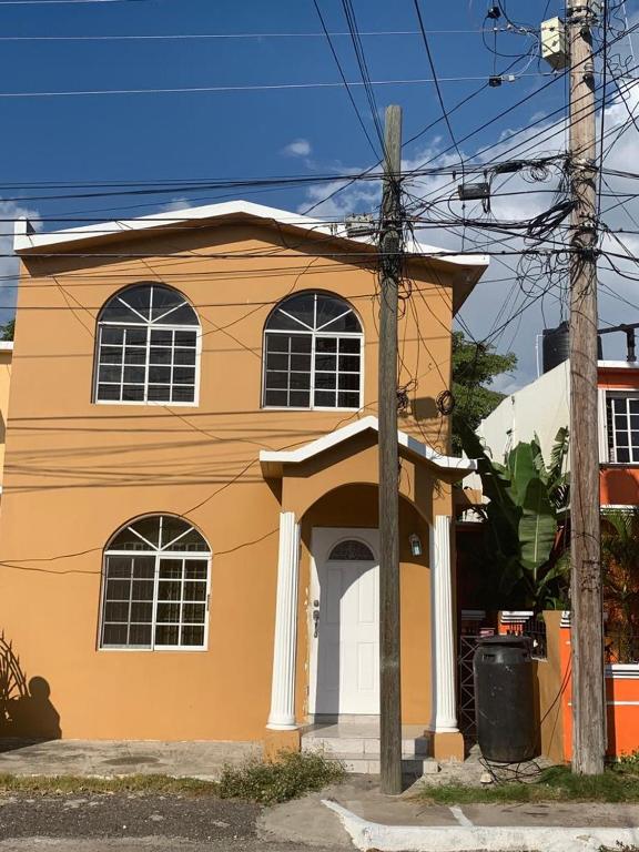 a orange and white house on a street at BridgeView Arcadia One in Portmore