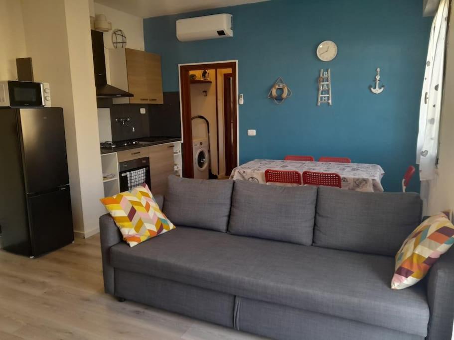 sala de estar con sofá gris y cocina en Appartamento a Ravenna - 100 metri dalla spiaggia en Lido Adriano