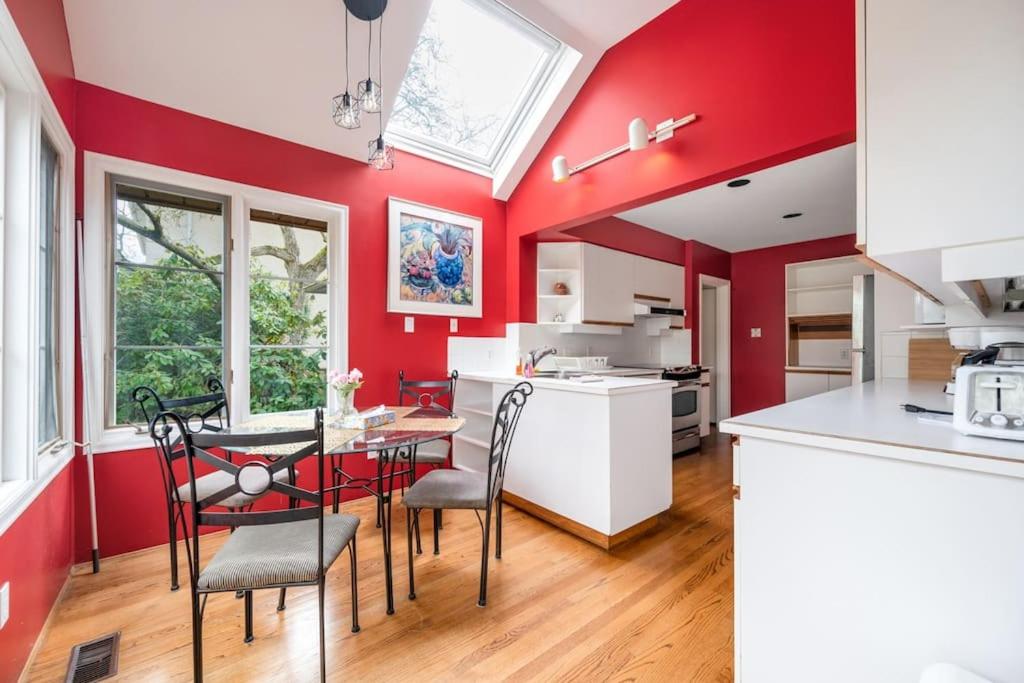 バンクーバーにあるTranquil Haven near Attractions: 4 BD Suiteの赤い壁のキッチン(テーブル、椅子付)