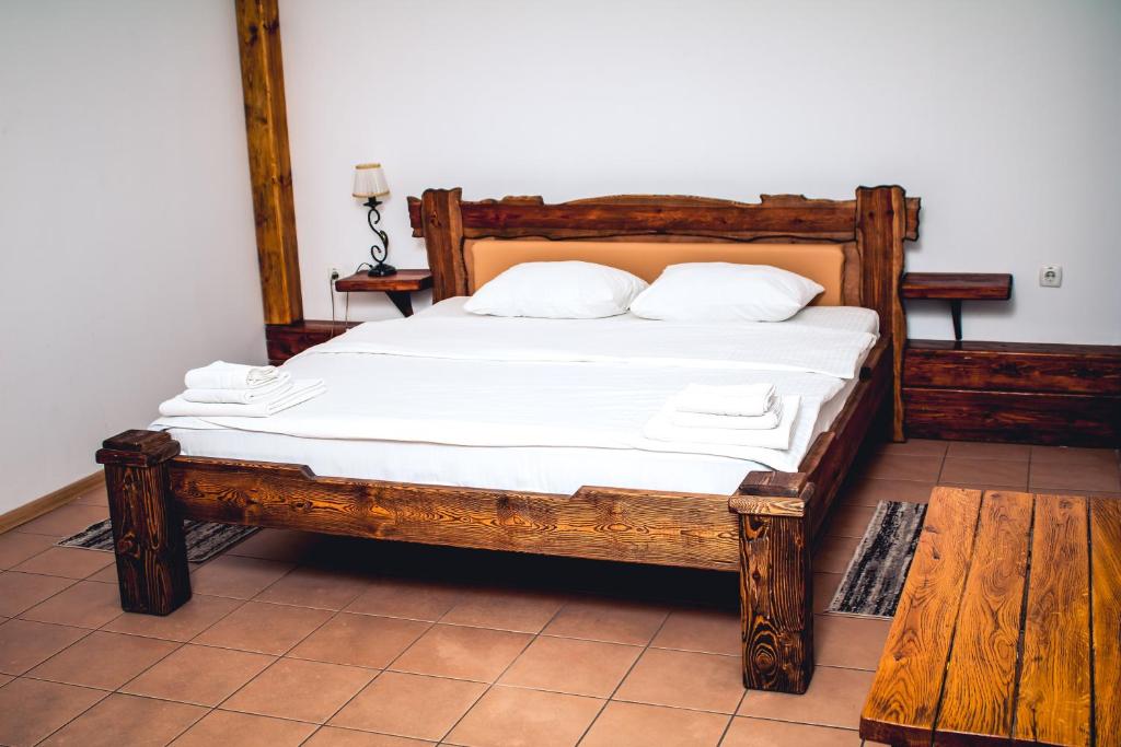 ein Schlafzimmer mit einem Holzbett und weißen Laken in der Unterkunft Fortetsya in Uman