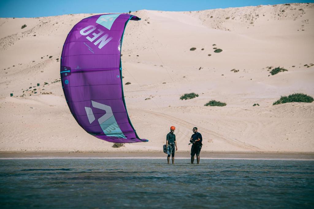 dos hombres parados en el agua con una cometa grande en PARAISO DAKHLA, en Dakhla