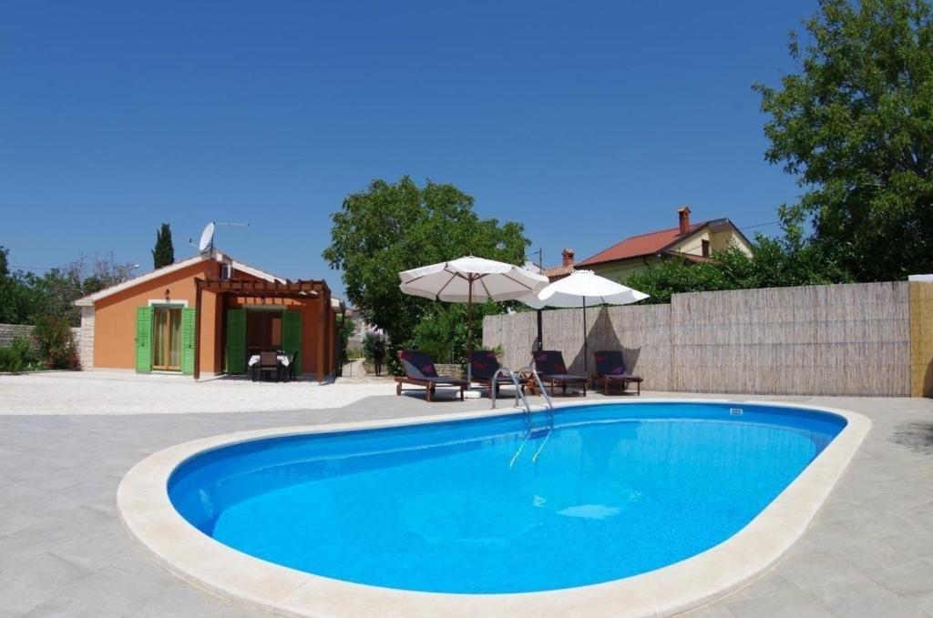 una piscina con 2 sillas y una sombrilla en Ferienhaus in Vodnjan mit Privatem Pool, en Vodnjan