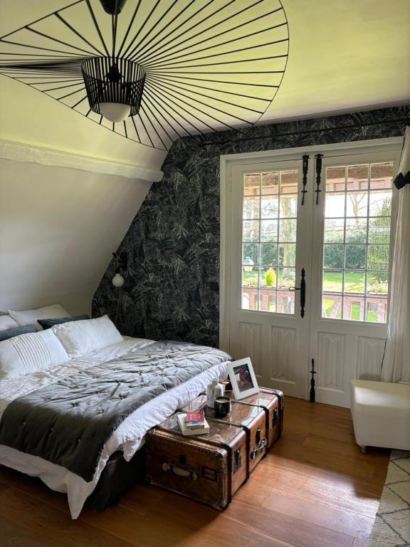 Schlafzimmer mit einem Bett mit einem Tisch und einem Kronleuchter in der Unterkunft Maison de charme, près des plages du Débarquement in Bayeux
