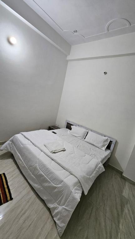 a white bedroom with a large bed with white sheets and pillows at Hotel Shri kishori farm in Mathura