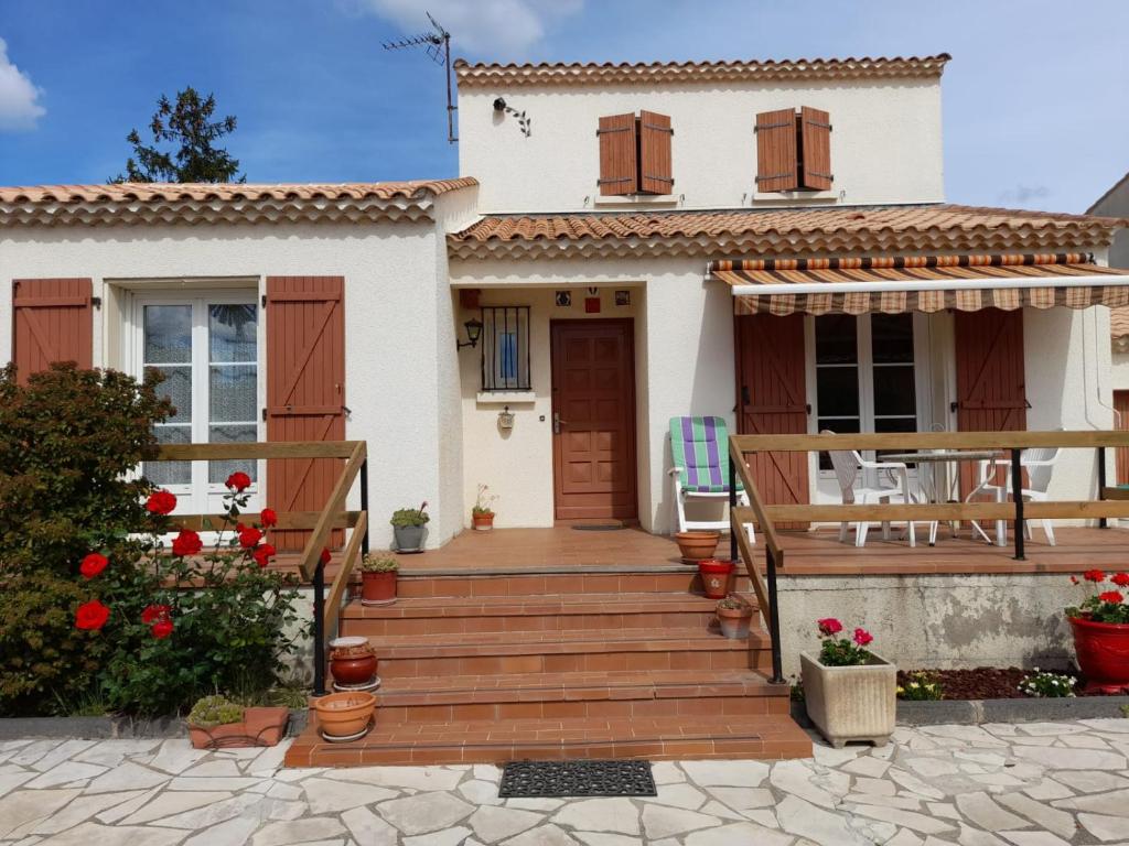 uma casa com uma escada de madeira que leva à porta da frente em Maison de Lili em Florensac