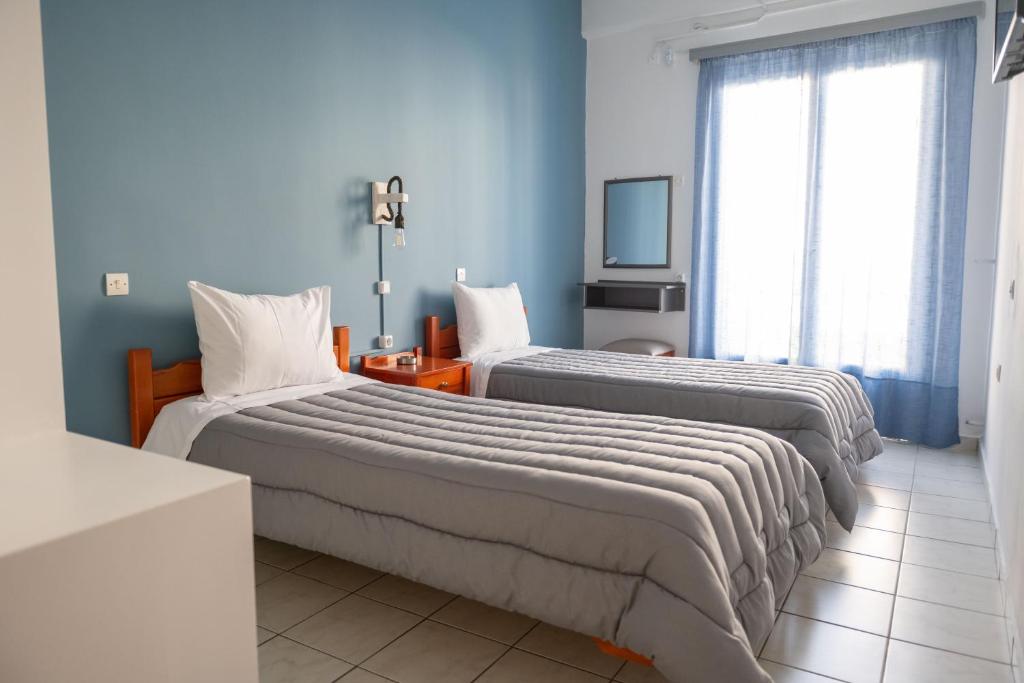 two beds in a room with blue walls at Hotel Theoxenia in Argos