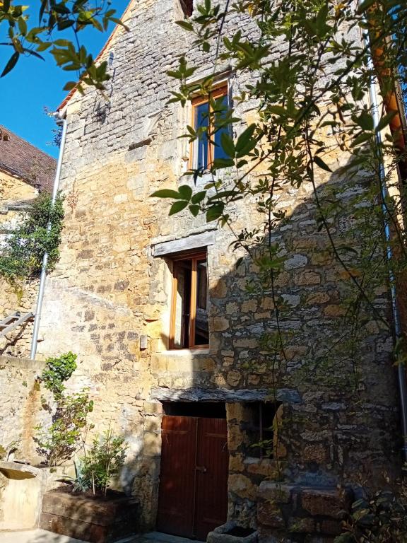 een stenen gebouw met een deur en een raam bij Maison de la Ruelle, vue sur les toits de Domme in Domme