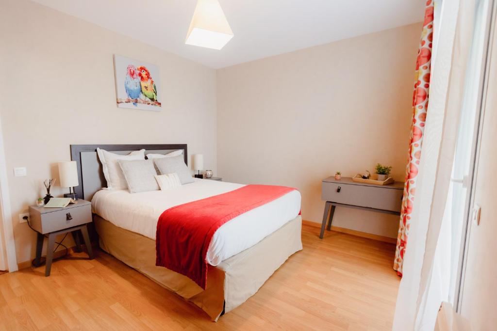 a bedroom with a large bed with a red blanket at Domitys Les Falaises Blanches in Bayeux