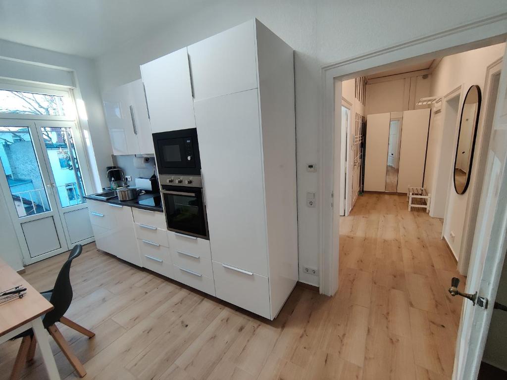 Il comprend une cuisine avec des placards blancs et du parquet. dans l'établissement City Apartments Offenbach, à Offenbach-sur-le-Main