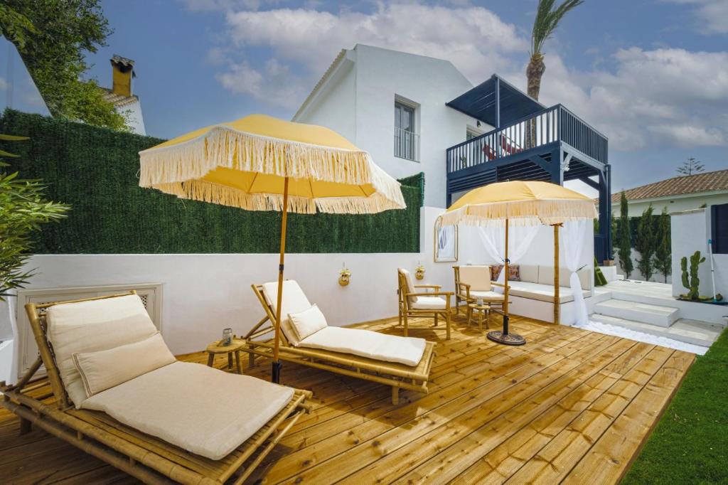 a deck with two chairs and two umbrellas at Escondite de Noah Grupo labreña in Los Caños de Meca