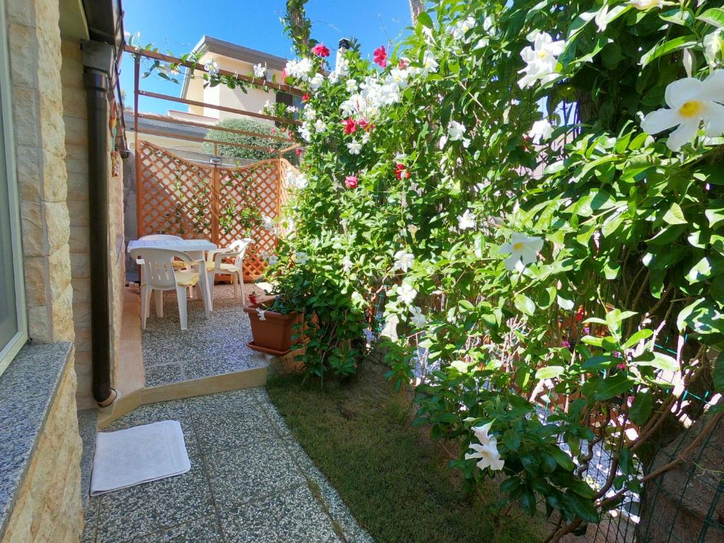 un jardín con flores, una mesa y un patio en Casa fiorita, en SantʼAndrea