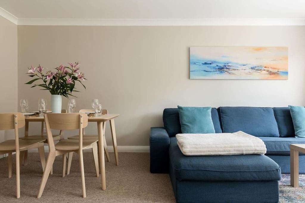 ein Wohnzimmer mit einem blauen Sofa und einem Tisch in der Unterkunft Bournemouth Sea Views, 2 Bed, lift, close to shops in Bournemouth