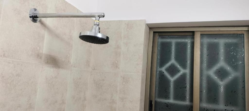 un cabezal de ducha en una pared junto a una ventana en Eco Living House- large group accommodation. en Varanasi