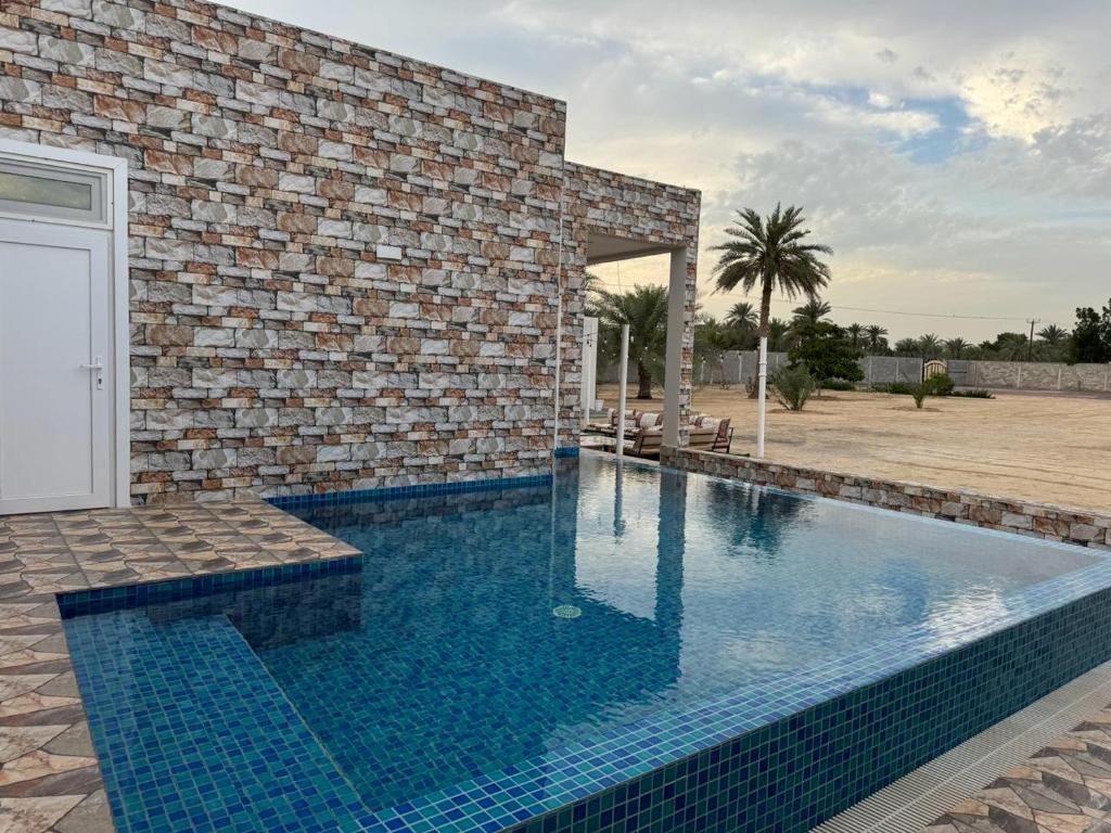 a swimming pool in front of a brick building at Rashed Farm in Al Rahba
