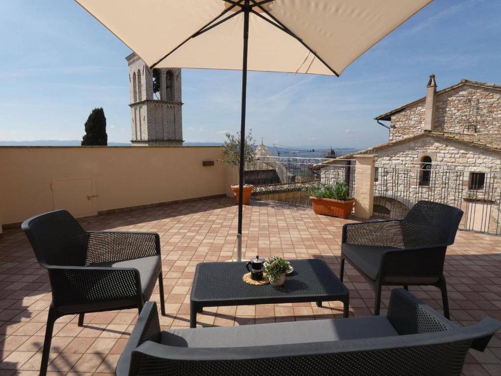 een patio met een tafel en stoelen en een parasol bij Scappo in Umbria, La casa di Eude in Assisi