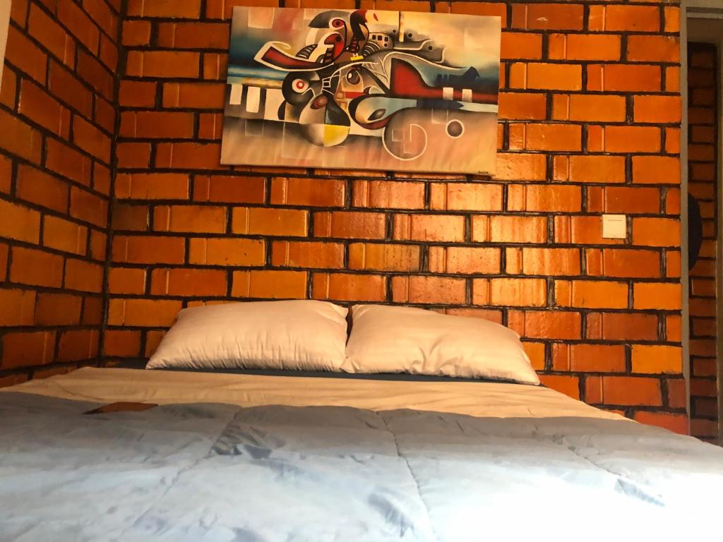 1 dormitorio con 1 cama y pared de ladrillo en Ginger Homes, en Mizingo