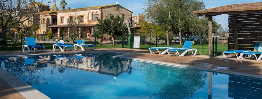 una piscina con sedie blu e un gruppo di Can Pujol - Turismo Rural a Serra de Daró