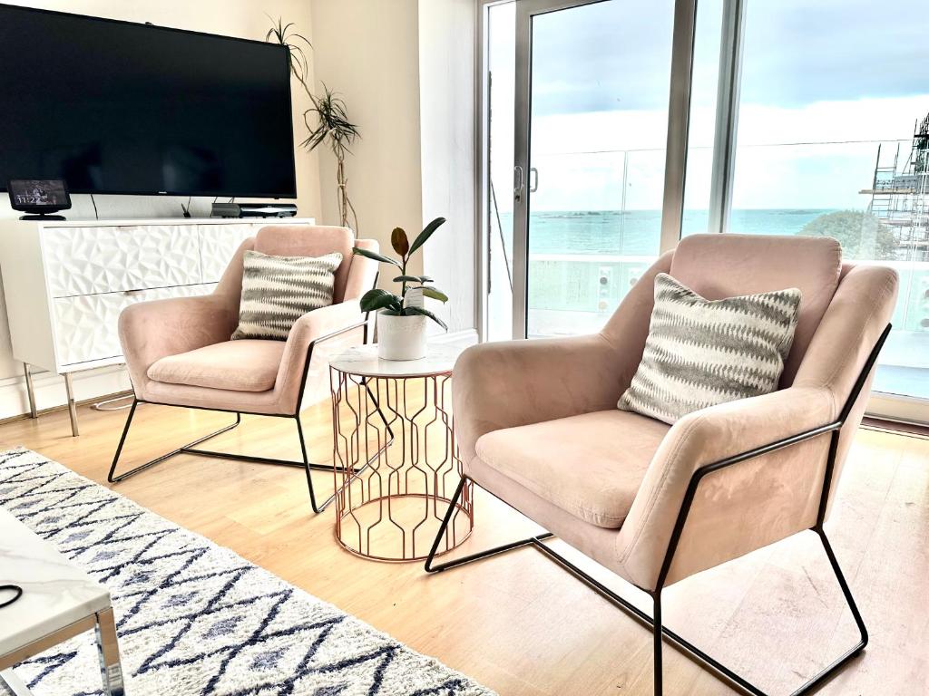 two chairs and a table in a living room with a tv at Eden House & Aquila House - Beach Apartments & Suites in Saint Helier Jersey