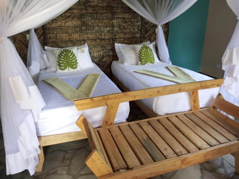 2 camas en una habitación con banco en Kazinga Wilderness Queen Elizabeth NP, en Katunguru