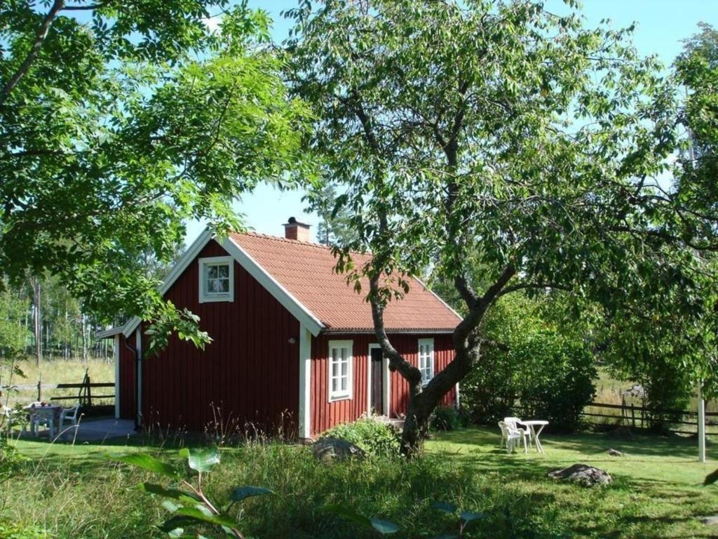 une maison rouge avec un arbre devant elle dans l'établissement Ferienhaus Nymåla, à Hultsfred