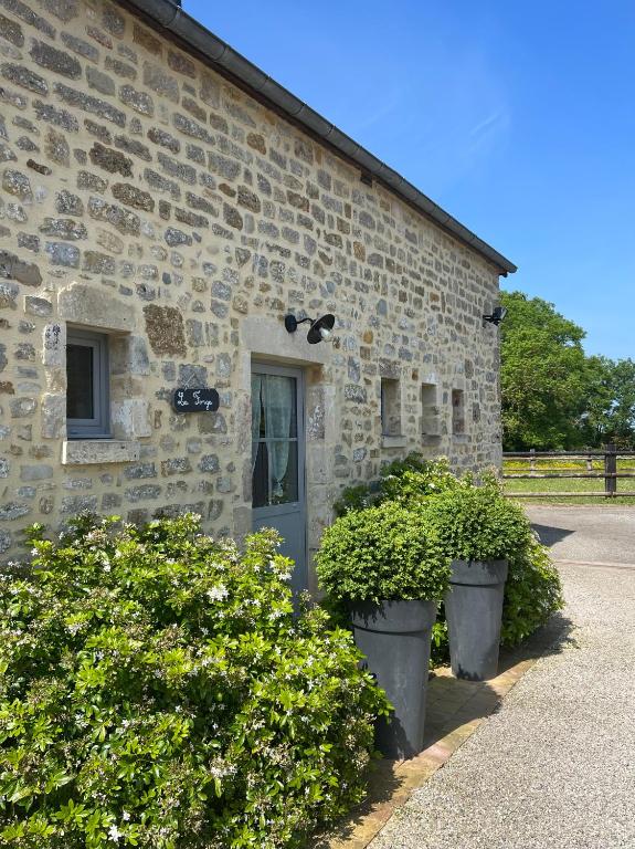 a stone building with two plants in front of it at La Forge, gîte familial,à Sainte Mère Eglise in Sainte-Mère-Église