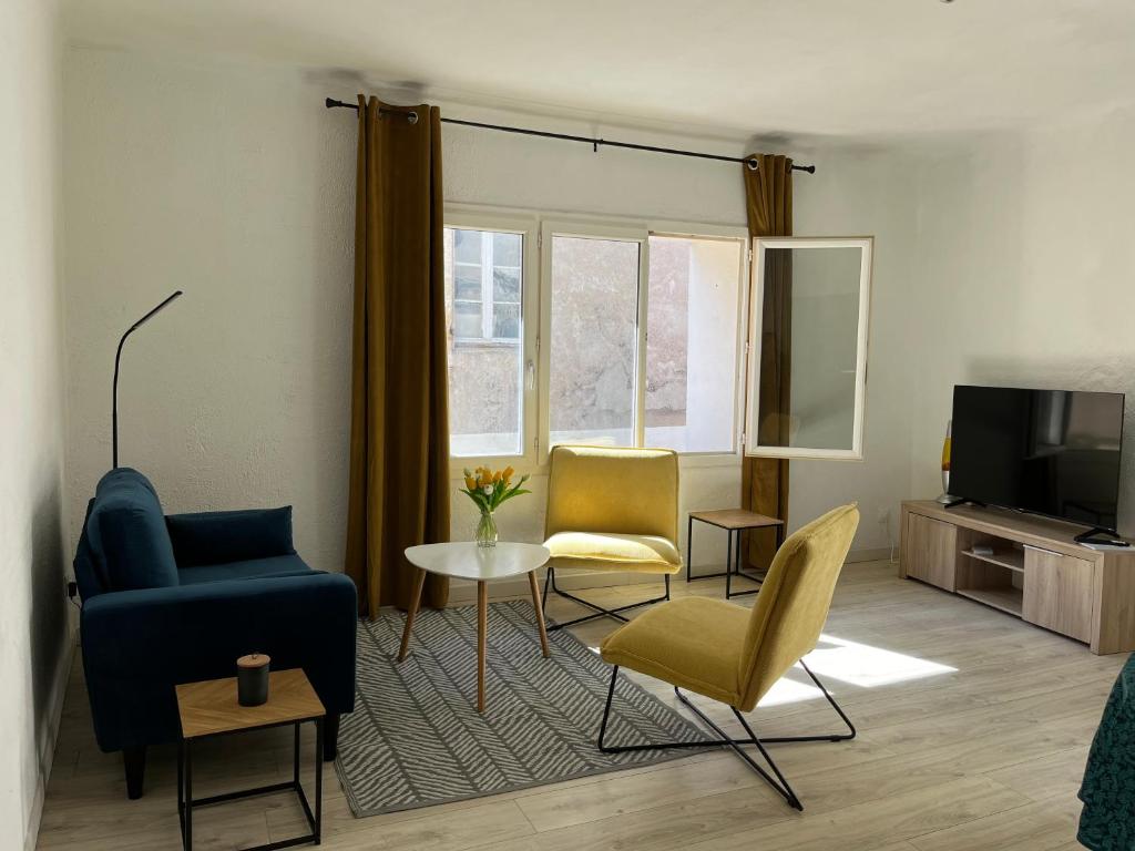 uma sala de estar com um sofá e cadeiras e uma televisão em Maison de village em Lédenon