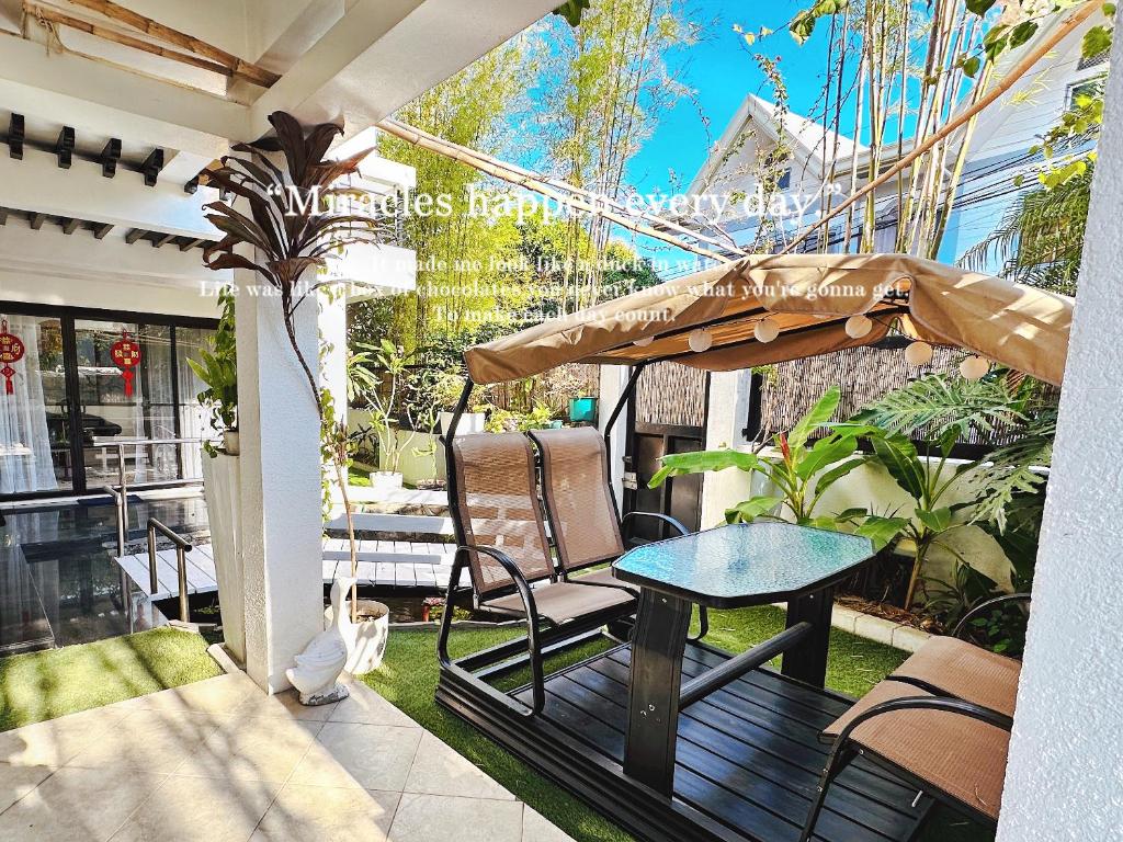 eine Terrasse mit einem Tisch, Stühlen und einem Sonnenschirm in der Unterkunft LarisZone-Luxury Courtyard Villa in Manila