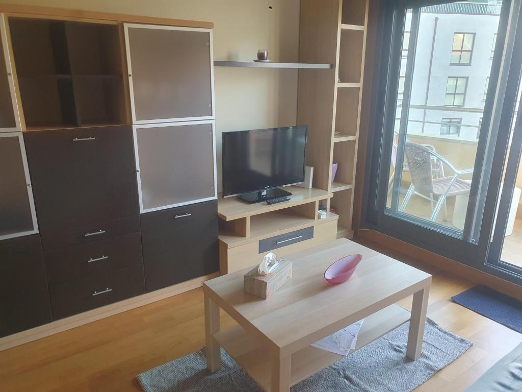 A television and/or entertainment centre at Apartamento en urbanización con piscina en Playa de Silgar