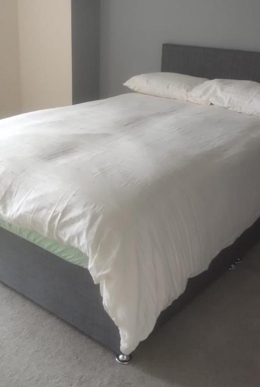 uma grande cama branca com lençóis e almofadas brancos em Telford Guest House 1 em Telford