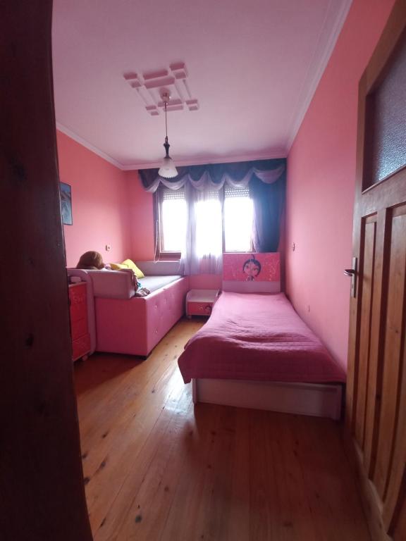 um quarto rosa com uma cama e um sofá em Къща село Катунци em Sandanski