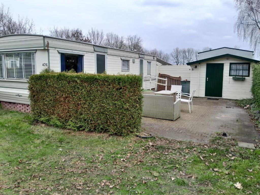 uma casa branca com uma sebe em frente a uma casa em Stacaravan 426 met airco vakantiepark de Tien Heugten Schoonloo Drenthe em Schoonloo