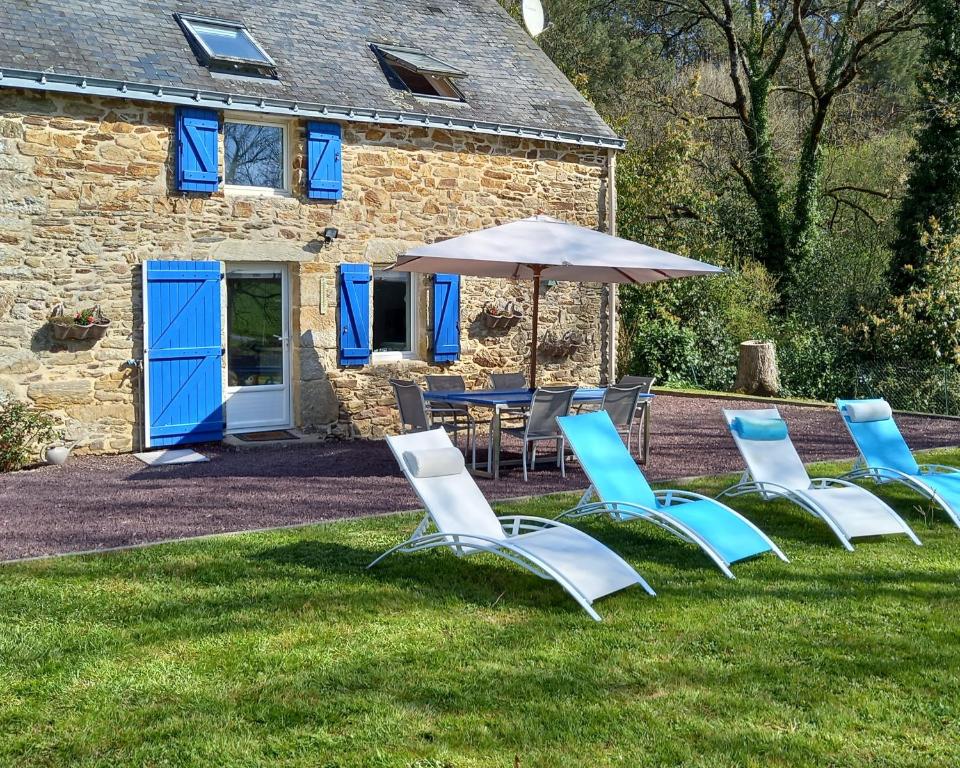 eine Gruppe Stühle und einen Tisch mit einem Sonnenschirm in der Unterkunft Charmante maison au calme in Marzan