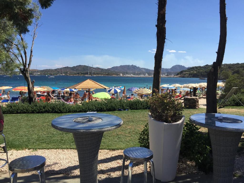 2 mesas y sillas y una playa con sombrillas en Luxury Apartment Sardegna, en Marina di Portisco