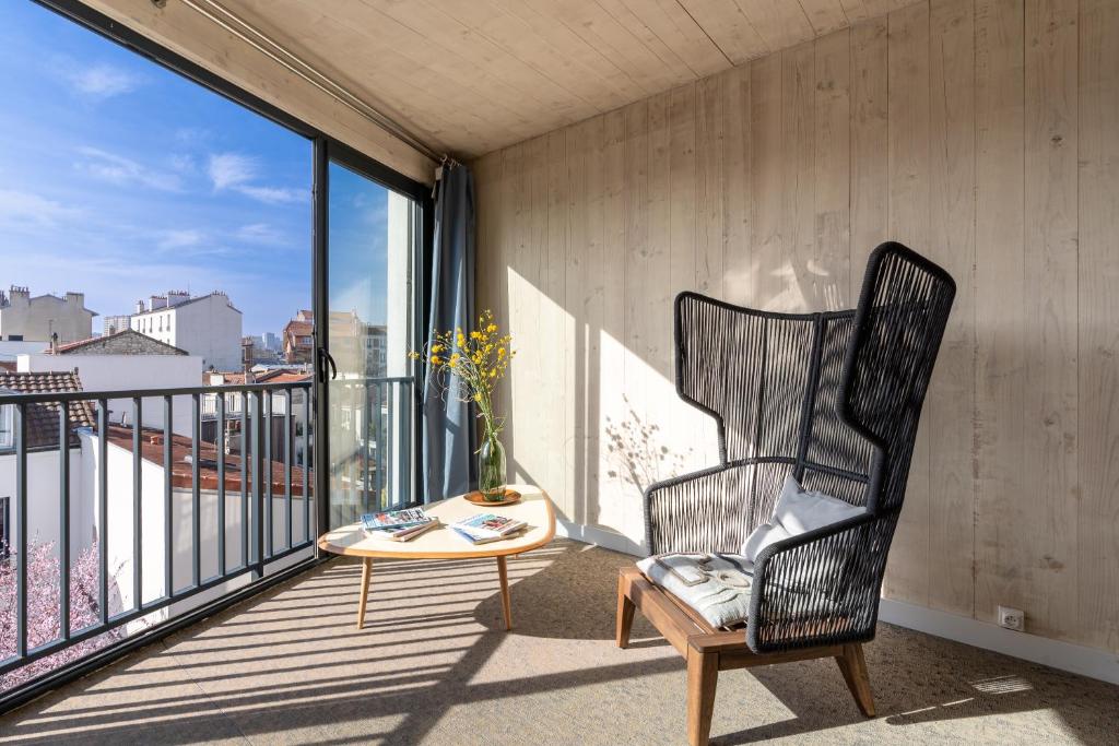 a rocking chair and a table on a balcony at Grand appartement moderne très proche de Paris centre in Malakoff