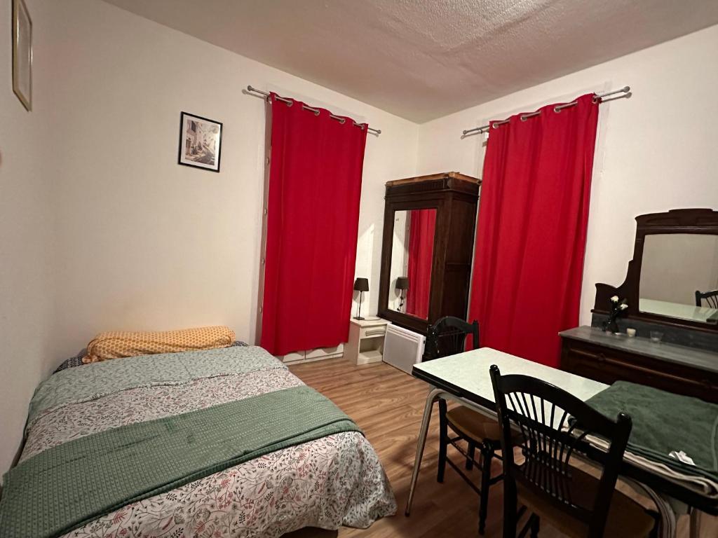 a bedroom with red curtains and a bed and a table at Charmant Studio avec Balcon in Perpignan