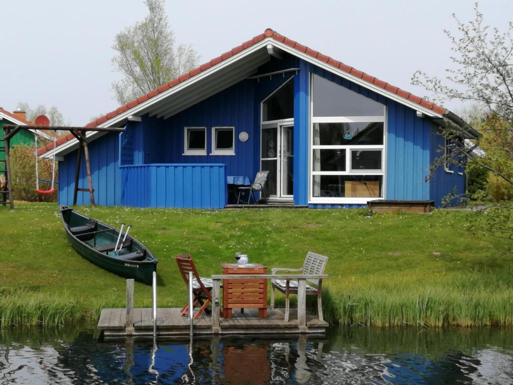 ein blaues Haus mit einem Tisch und Stühlen auf dem Wasser in der Unterkunft Ferienhaus Kormoran in Otterndorf