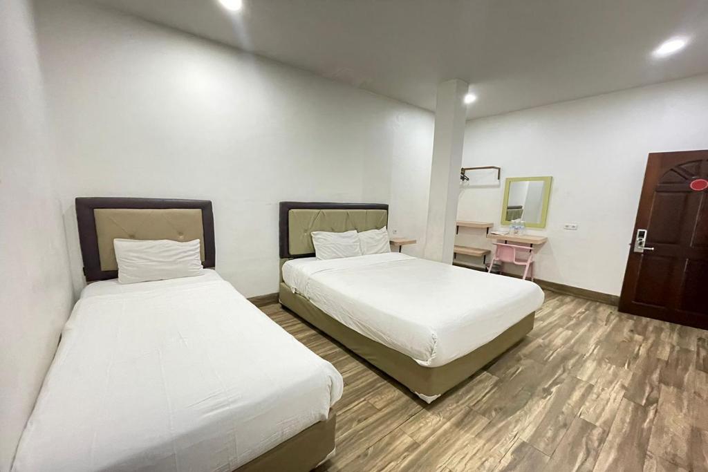 a room with two beds and a desk with a mirror at Residence 8 in Palembang