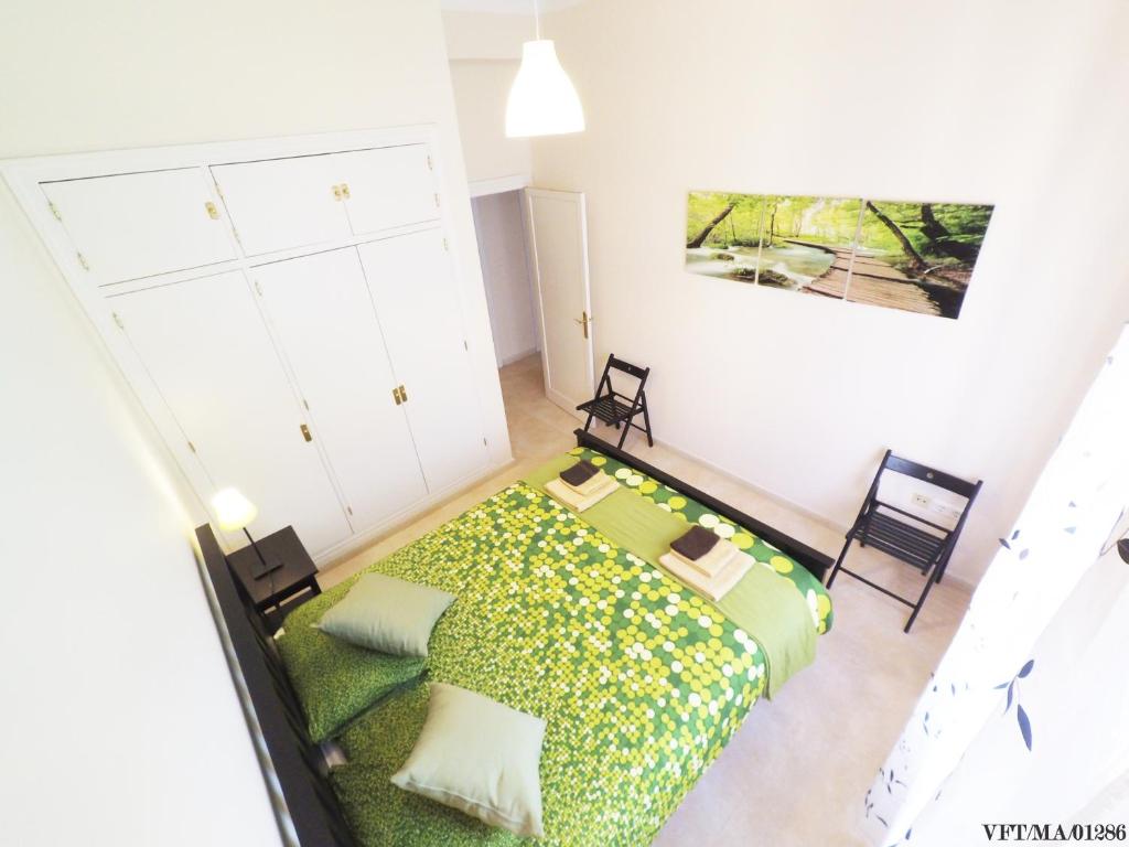 1 dormitorio con 1 cama verde y 2 sillas en Apartamento Heredia 20 - Harbour, en Málaga