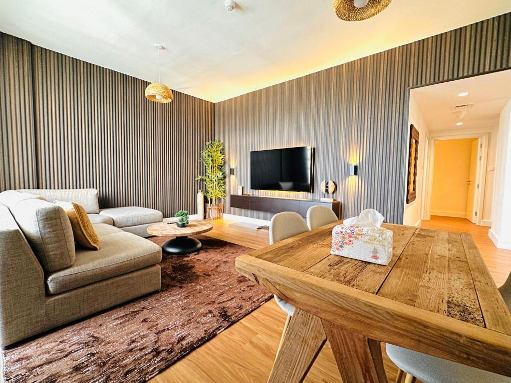 sala de estar con mesa y sofá en 2 Bedroom WoodHouse By Blue Holidays, en Sharjah